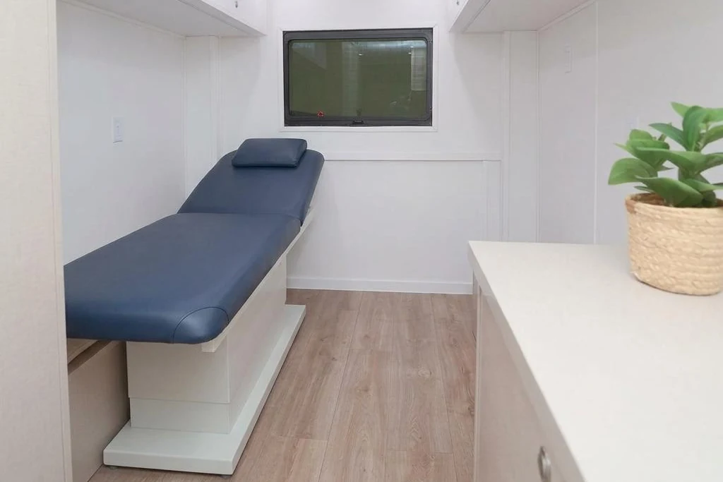 Private Mobile Medical Office exam room with a compact wall-aligned exam chair and clear aisle
